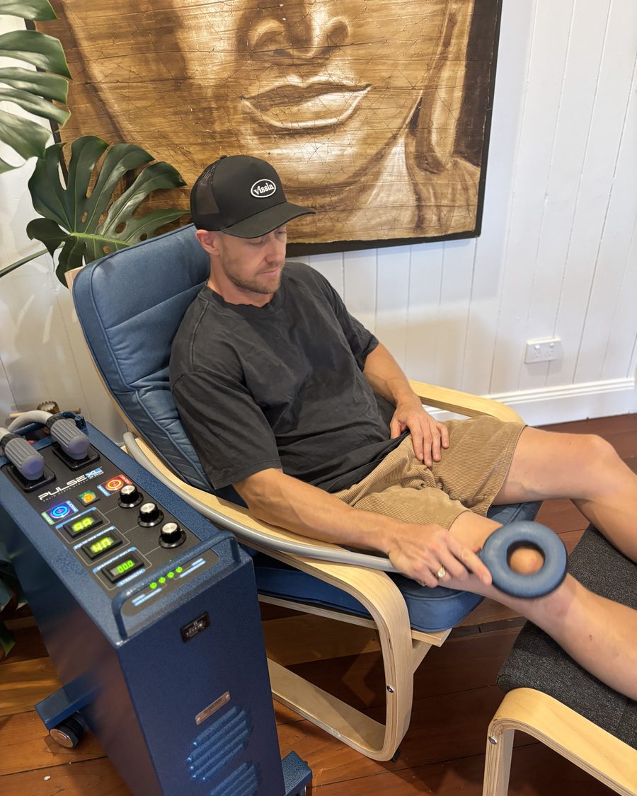 A client relaxing in the Nu Wave chair during a PEMF session, applicator resting on the knee